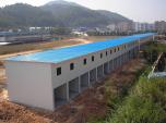 Long steel building with a blue roof and grey-white walls
