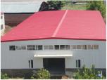 Steel building with a red roof and grey-white walls