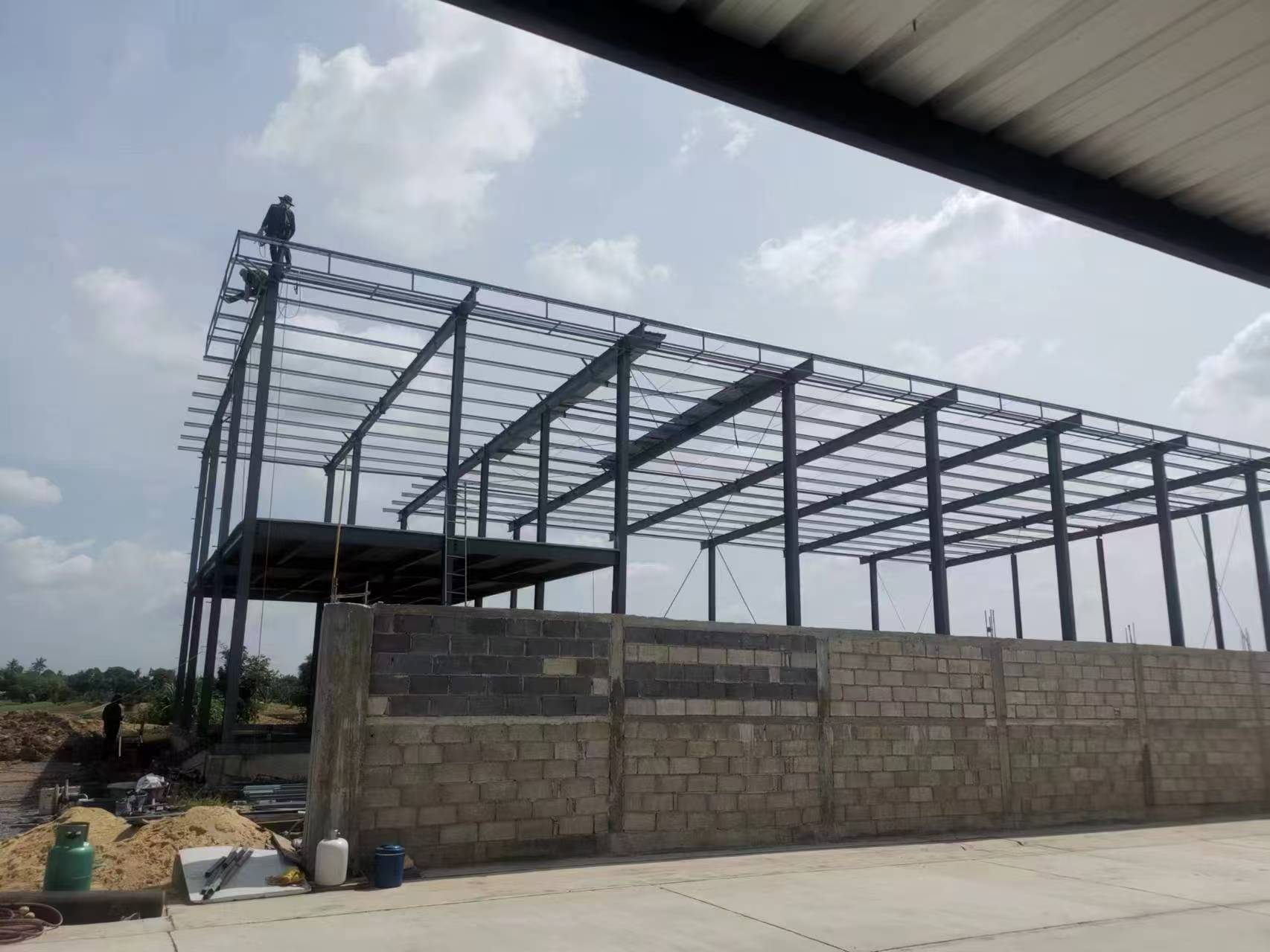 Thailand steel workshop frame with roof members and masonry wall during enclosure progress