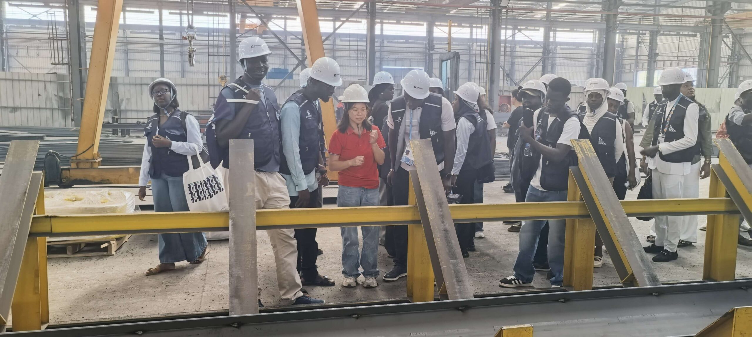 Visitors listening to the Ganyo team beside steel structure production equipment.